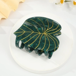 Détail de la pince à cheveux en forme de feuille d'acétate vert foncé et nervures dorées