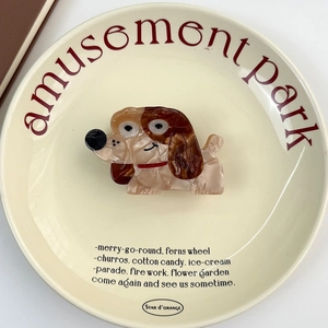 Vue détaillée d'une pince à cheveux en acétate en forme de chien avec strass sur assiette décorative