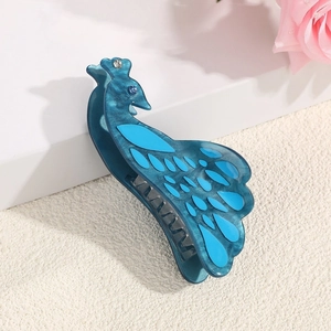 Elegant peacock acetate hair claw clip with blue rhinestones on a white pedestal