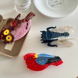 Vibrant acetate animal hair claw clips featuring owl and parrot designs on white surface
