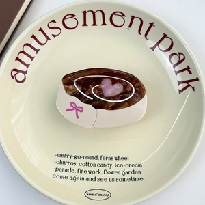 Détail d'un support de téléphone en écaille avec cœurs roses sur une assiette crème