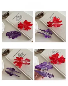Detail view of goldfish claw clips in red and purple acetate with fine scales