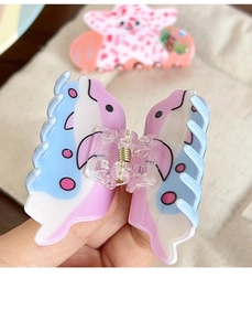 Détail d'une pince à cheveux papillon dauphin brillante avec motifs marins colorés