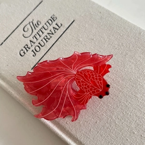 Detailed macro view of translucent red goldfish hair claw clip with white scale patterns