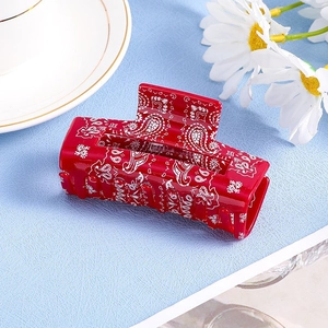 Detail of red paisley hair claw clip with white bohemian pattern on blue background