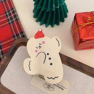 Detail of cute bear hair claw with red Christmas hat on festive holiday background