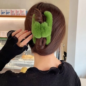 Détail d'une pince à cheveux en fausse fourrure verte douce pour un chignon élégant