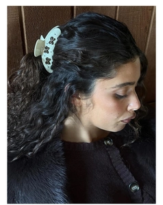 Detail of cream acetate hair claw clip with black floral accents worn on dark hair