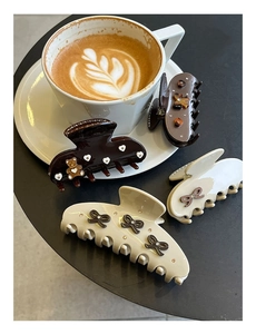 Detailed close-up of brown bow hair claws with rhinestone and bear motifs on coffee table