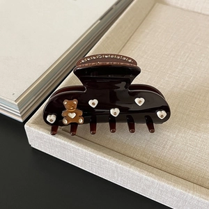 Macro view of brown acetate hair claw featuring 3D bear and sparkling heart rhinestones