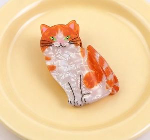 Detail einer süßen Haarklammer in Katzenform aus marmoriertem Acetat in Orange und Weiß