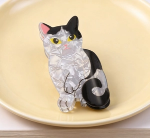 Detailaufnahme einer weiß-schwarzen Katzen-Haarklammer aus Acetat auf einem Keramikteller