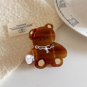 Vue détaillée d'une pince à cheveux ours en acétate marron avec un nœud rouge vif