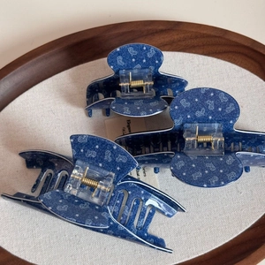 Drei blaue Haarklammern mit Herzprint und Goldfedern in einer Holzschale