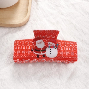 Détail d'une pince à cheveux rouge de Noël avec motifs de Père Noël sur plateau bois