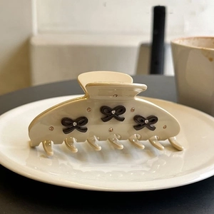 Creamy acetate hair claw clip with black bows and rhinestones in an elegant setting