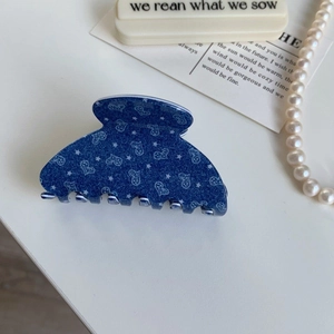 Close-up of large blue heart print acetate hair claw clip with denim pattern design