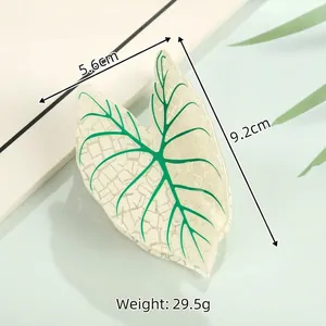 Detail view of leaf-shaped acetate hair claw clip with size dimensions 9.2cm and 5.6cm
