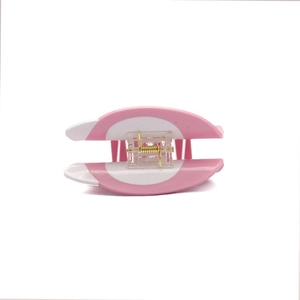 Close-up detail of pink and white acetate hair claw clip with golden metal spring