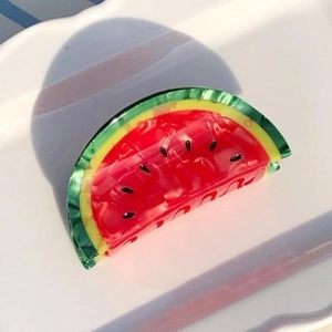 Pince à cheveux en acétate en forme de pastèque sur une assiette en céramique