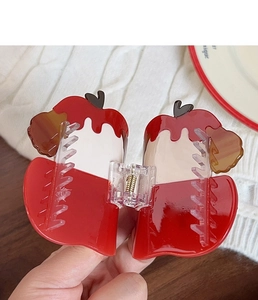 Detail of red and cream apple claw clip with glossy finish and sturdy metal spring