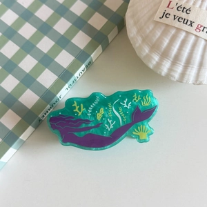 Detailed close-up of a teal acrylic hair claw featuring a purple mermaid and sea plants