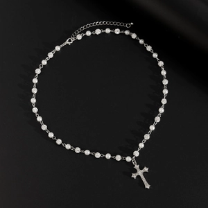 Dettaglio della collana a croce hip-hop con perle e sfere di strass su sfondo nero