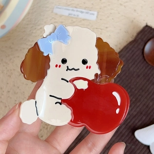 Detail view of large acetate poodle hair claw clip with red apple and blue bow accent