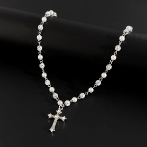 Dettaglio ravvicinato di collana di perle con pendente a croce diamantata su supporto nero