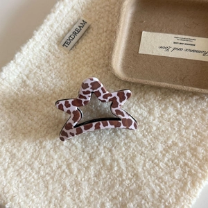 Dettaglio di un fermaglio per capelli a forma di stella con stampa leopardata su fondo di lana