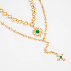 Vue détaillée du collier à plusieurs rangs avec croix dorée et pendentif fleur verte