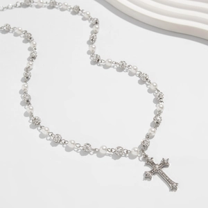 Dettaglio della collana con croce d'argento, perle bianche e sfere di strass