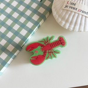 Detailed top view of a lobster-shaped acrylic hair claw clip on a minimal desk setup