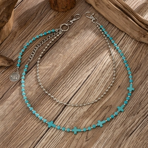 Detail of turquoise beaded waist chain with silver crosses and compass charm on wood