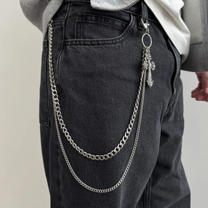 Detail of silver double-layered metal trousers chain with vintage cross pendant on jeans