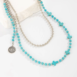 Detail of layered turquoise beaded chain with silver cross and star moon pendant