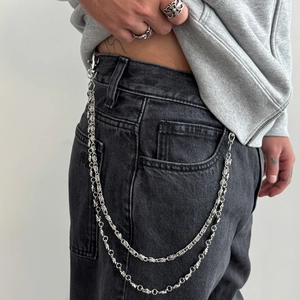 Detail showing heavy metal double layer cross chain with large spring clasp on black jeans