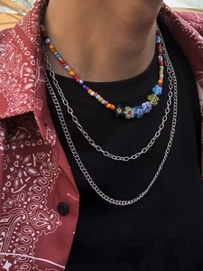 Gros plan sur un ensemble de colliers avec perles colorées, fleurs en résine et chaînes argent