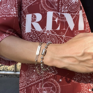 Close-up of dual-layer bracelet with paperclip links, bead chain and engraved metal tag