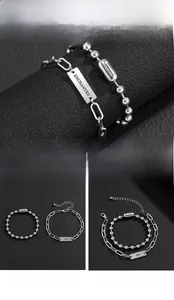 Detail of silver stainless steel double chain bracelet with Enchanted engraved metal tag