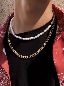 Close-up of double-layer men's necklace with white pearls and golden Figaro chain