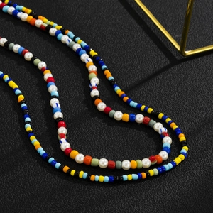 Detail shot of colorful bohemian seed bead necklace with white pearls on a black leather background