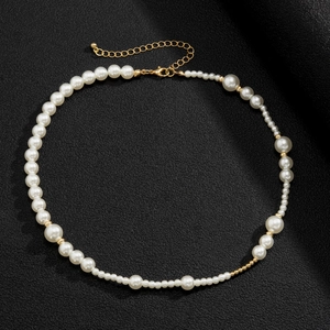 Detail van witte parelketting met gouden kralen op een zwarte getextureerde achtergrond