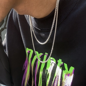 Dettaglio di collane a catena in metallo argento a strati su una felpa streetwear