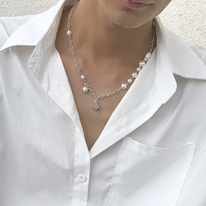 Detail of a pearl and silver chain necklace featuring a unique metal dice pendant for men