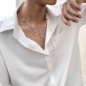 Men's fashion necklace with white pearls and a metal dice pendant on a white shirt