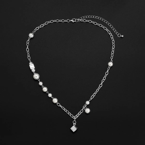 Detail view of pearl and chain necklace with silver dice pendants on black background