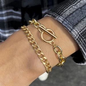 Close-up of gold double-layer chain bracelets with OT toggle clasp and curb link design
