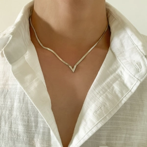 Collar de cadena de serpiente plateada en forma de V con una camisa de lino blanca