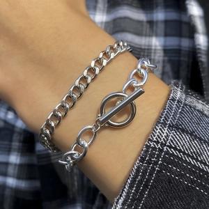 Detail of layered silver Cuban chain and oval links bracelet with a stylish OT toggle clasp